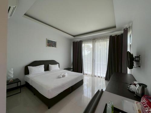 a bedroom with a white bed and a large window at Nutchana Hill Boutique Hotel in Ban Thung Ri