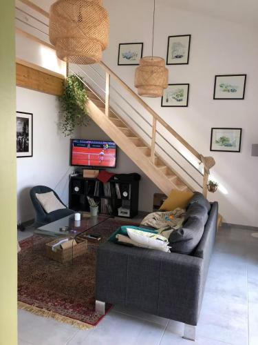 a living room with a couch and a staircase at Chambre paisible proche Centre Ville in Saint-Yrieix-sur-Charente