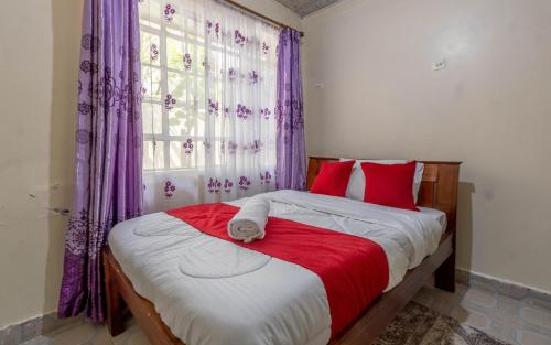 a bedroom with a bed with red pillows and a window at Bremu homes near JKIA airport. in Nairobi