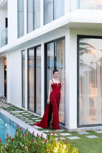 a woman in a red dress standing in front of a building at Hoi An Royal Beachfront Villas in Dien Ban