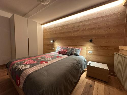a bedroom with a bed with a wooden wall at Affittacamere Tarvisio in Tarvisio