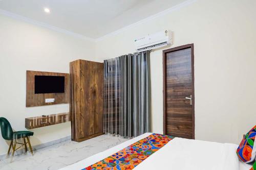a bedroom with a bed and a tv and a window at FabHotel The Glampoint in Noida