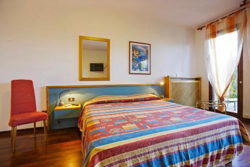 a bedroom with a bed and a chair and a mirror at Residenz Moncucco in Luino
