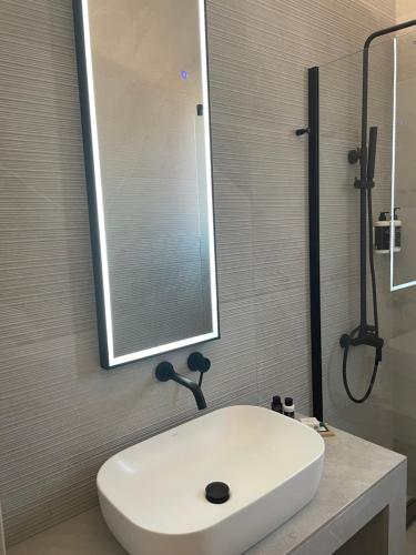 a bathroom with a white sink and a mirror at Nõs Luxury Rooms in Mesolongion