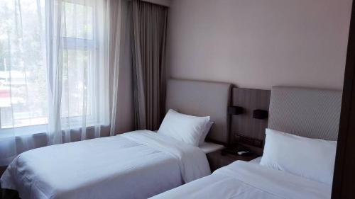 a hotel room with two beds and a window at Hanting Hotel Beijing Temple of Heaven in Beijing