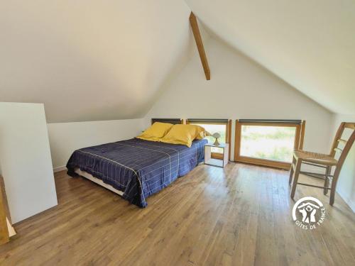 a bedroom with a bed and a chair in a attic at Les Petites Fontenelles in Montjean