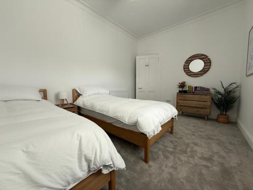 Un dormitorio con dos camas y un espejo en la pared. en Bay View Cottage, en Fairlie