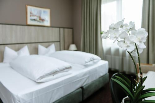 a bedroom with two beds with white sheets and a flower at ROSS Hotel nähe Messe Stuttgart in Stuttgart