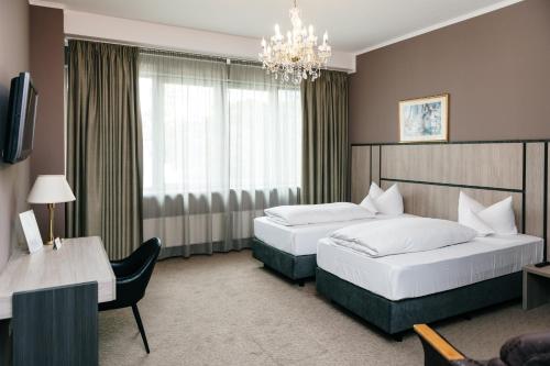 a hotel room with two beds and a chandelier at ROSS Hotel nähe Messe Stuttgart in Stuttgart
