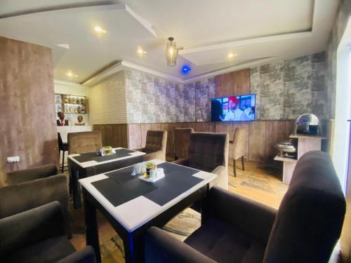 a restaurant with tables and chairs and a tv at PRESKEN WHITE HOUSE in Lagos