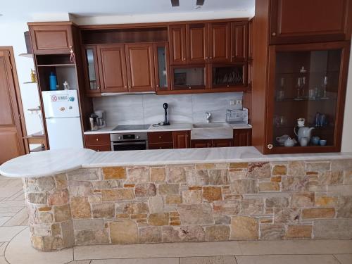 a kitchen with wooden cabinets and a stone counter top at Apartment with a garden, BBQ, swimming pool and jacuzzi in Drafí