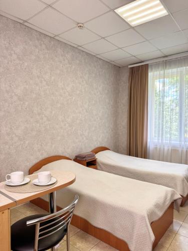 a hotel room with two beds and a table and chairs at Hotel Vesta in Brovary