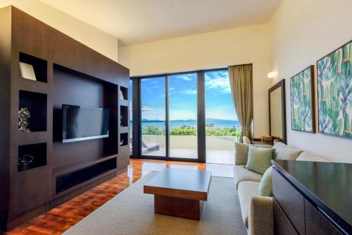 a living room with a couch and a tv at アイネスヴィラノッツェ沖縄 in Nago