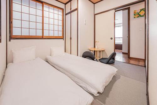 two beds in a room with a table and chairs at Tokyo Stay House Hirai in Tokyo