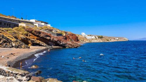 a group of people in the water at a beach at Santorini's Old Mill Serene Getaway by Pori Beach in Vourvoulos
