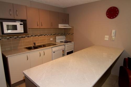 a kitchen with white cabinets and a counter top at Merrima Court Holidays in Caloundra