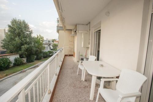 a balcony with white chairs and a table at Thessaloniki Blue Escape by ΜΡS in Perea