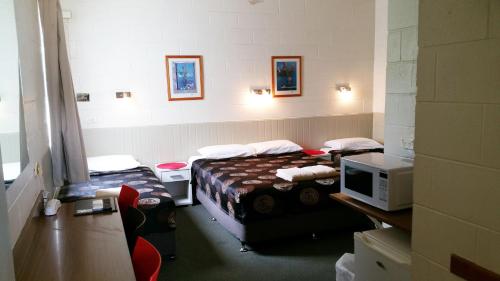 a room with two beds and a desk with a microwave at A&A Lodge Motel in Emerald