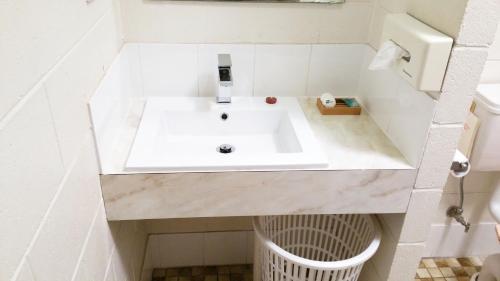 een badkamer met een witte wastafel en een vuilnisbak bij A&A Lodge Motel in Emerald