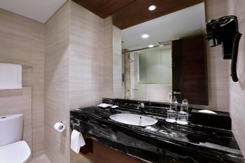 a bathroom with a sink and a toilet and a mirror at Aston Pasteur in Bandung