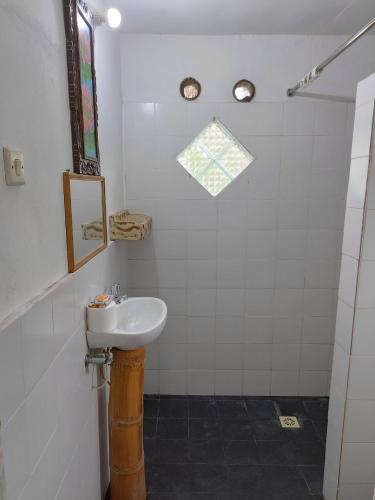 a white bathroom with a sink and a shower at D'Bulan bungalows and kafe in Tetebatu