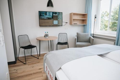 a bedroom with a bed and a table and chairs at Coffee Fellows Hotel & Longstay in Pfaffenhofen an der Ilm