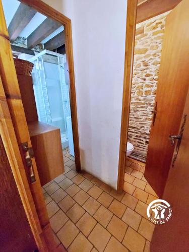 a hallway with a door to a room with a stone wall at La Herrière in Méral