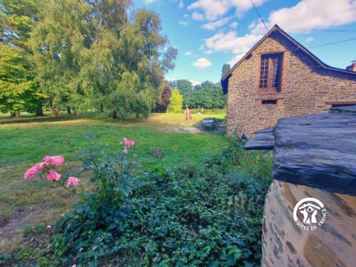 an old brick house with flowers in a yard at La Herrière in Méral