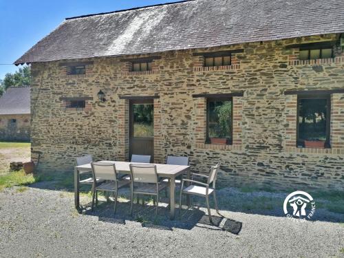 a table and chairs in front of a stone building at La Herrière in Méral