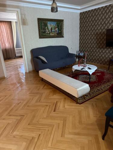 a living room with a blue couch and a wooden floor at gaydi in Gori