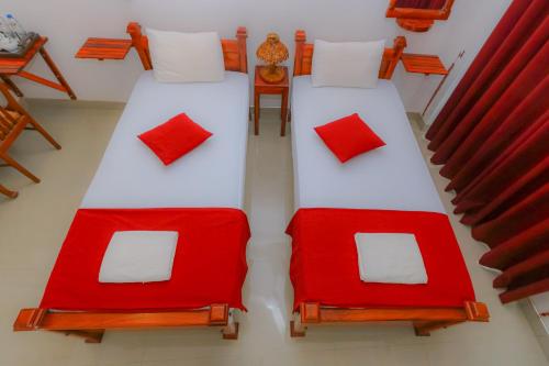 two beds with red and white pillows in a room at Castle Resort Yala in Tissamaharama