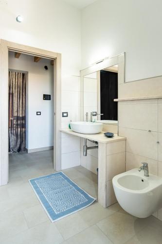 a bathroom with a sink and a toilet and a mirror at Ale house experience in Riola Sardo