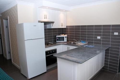 Una cocina con electrodomésticos blancos y un refrigerador blanco. en The Swiss Motel, en Cooma