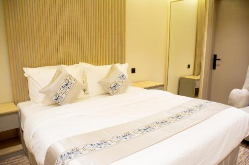 a bedroom with a large white bed with pillows at ﺳﹻﻠﹿﺲ ﻟﻠﺸﻘﻖ اﻟﻤﺨﺪومة - الروابي in Riyadh
