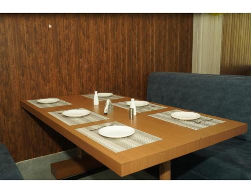 a wooden table with plates and napkins on it at Hotel Dynasty, Deoghar, in Deoghar