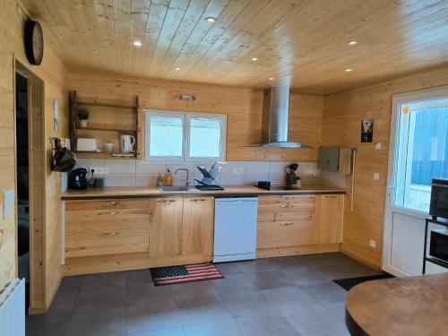 a kitchen with wooden cabinets and a white refrigerator at GITE A THEME D-DAY - situé à 15mn d'Omaha Beach - Animaux OK - Terrain clos - Aucuns voisins in Cartigny-lʼÉpinay