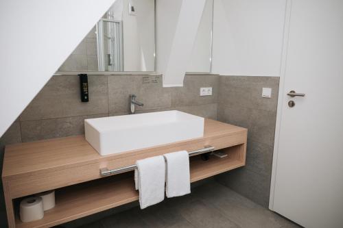 a bathroom with a white sink and a mirror at Coffee Fellows Hotel & Longstay in Pfaffenhofen an der Ilm
