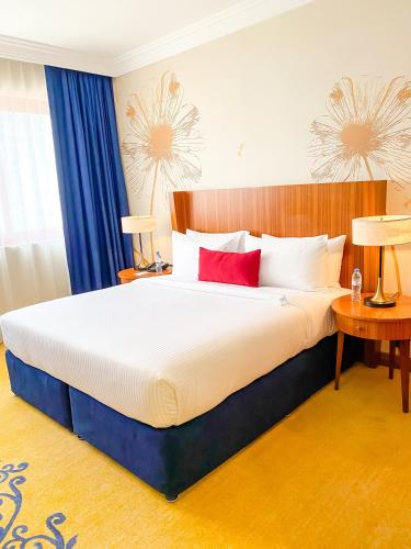 a bedroom with a large bed with red pillows at City Seasons Al Hamra Hotel in Abu Dhabi