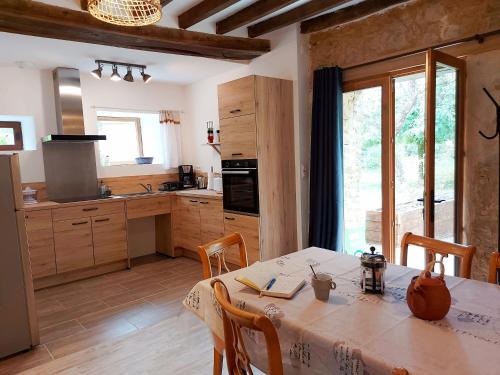 a kitchen with a table with chairs and a kitchen with a window at La Petite Maison in Vaiges