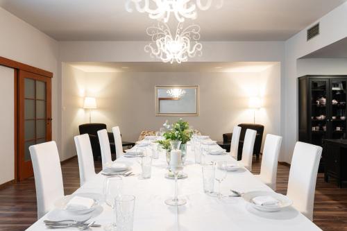 a long table with white chairs and a chandelier at Hotel Maroli Mikulov in Mikulov