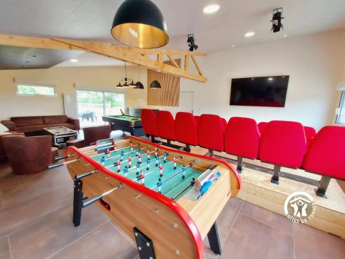 a living room with a ping pong table and red chairs at Un instant à Saulges, jusqu'à 12 personnes in Saulges