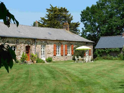 a stone house with a table and an umbrella at Le Gîte Susan in La Douaire