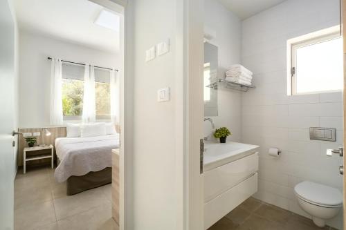 a white bathroom with a toilet and a bed at Keshet Eilon Galilee Views Retreat by Sea N' Rent in Elon