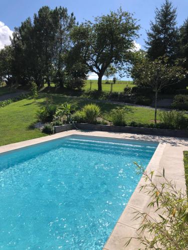 a swimming pool with blue water in a yard at L'étoile du Berger in Montsûrs