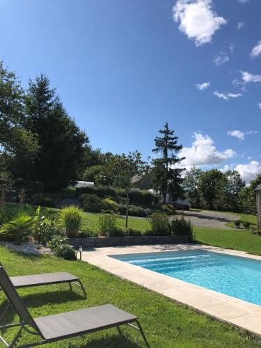 a swimming pool with two lawn chairs next to it at L'étoile du Berger in Montsûrs