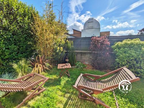 two wooden benches in a garden with a observatory at Le Pêcheur d'étoiles in Origné