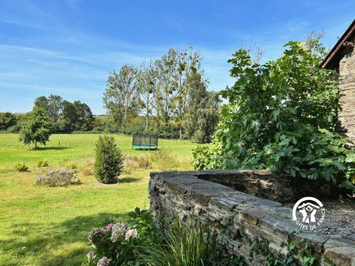 a garden with a stone wall and a field at Le Moulin Renaud, 8 personnes 