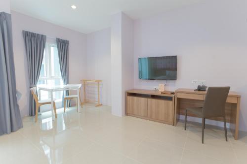 a living room with a television and a table and chairs at The Bedroom Ladprao 101 Bangkok - SHA in Bangkok