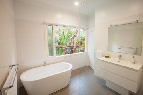 a white bathroom with a tub and a sink at The Mill Apartments Clare Valley in Clare