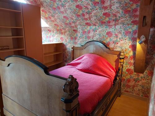 a bedroom with a bed with pink sheets and floral wallpaper at Gîte de la Houzardière, jusqu'à 7 pers in Bazougers
